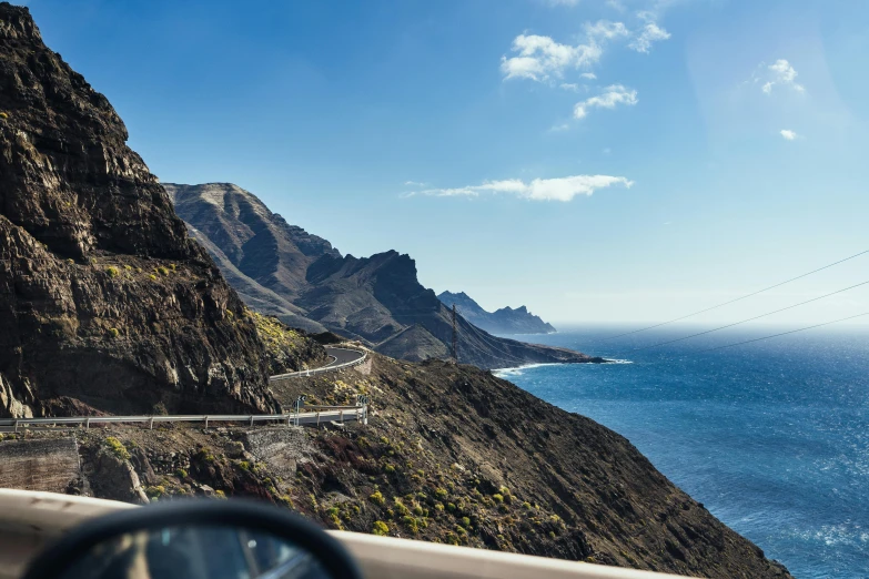 a car driving down a road next to the ocean, by Julia Pishtar, pexels contest winner, sharp cliffs, 🚿🗝📝