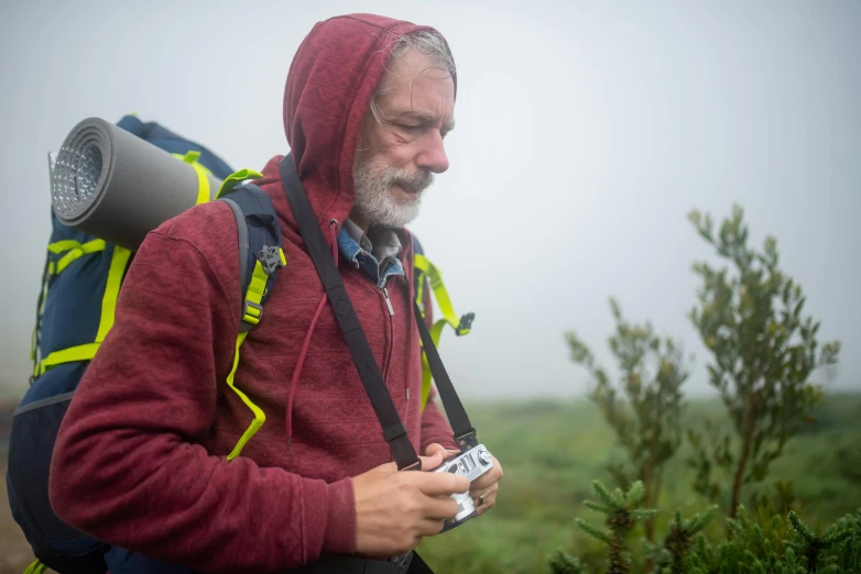 a man with a backpack and a camera, by Jóhannes Geir Jónsson, plein air, foggy photo 8 k, color photograph portrait 4k, grey beard, candid photograph