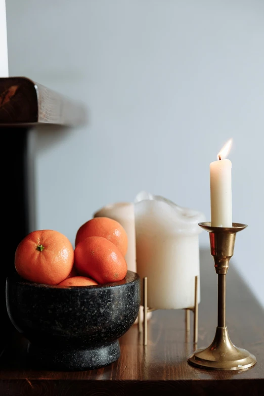 a wooden table topped with a bowl of fruit and a candle, trending on unsplash, baroque, on a candle holder, dwell, high resolution product photo, light lighting side view