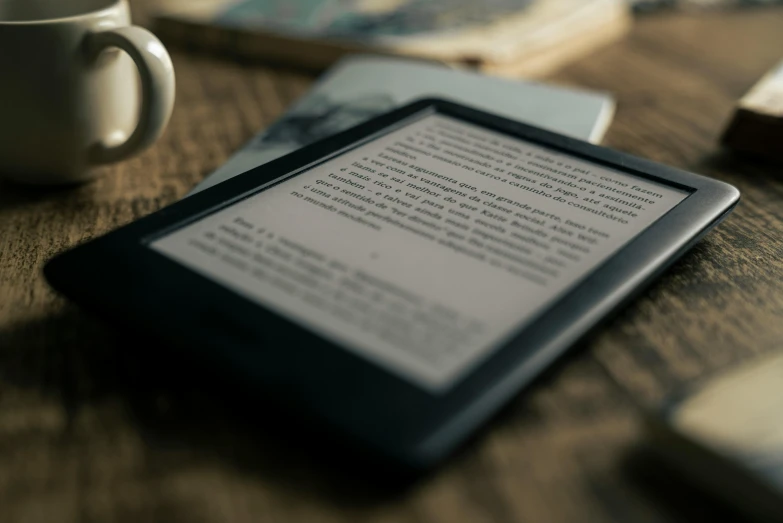 a tablet computer sitting on top of a wooden table, by Carey Morris, pexels, figuration libre, books on side table, teaser, ko-fi, rim lit