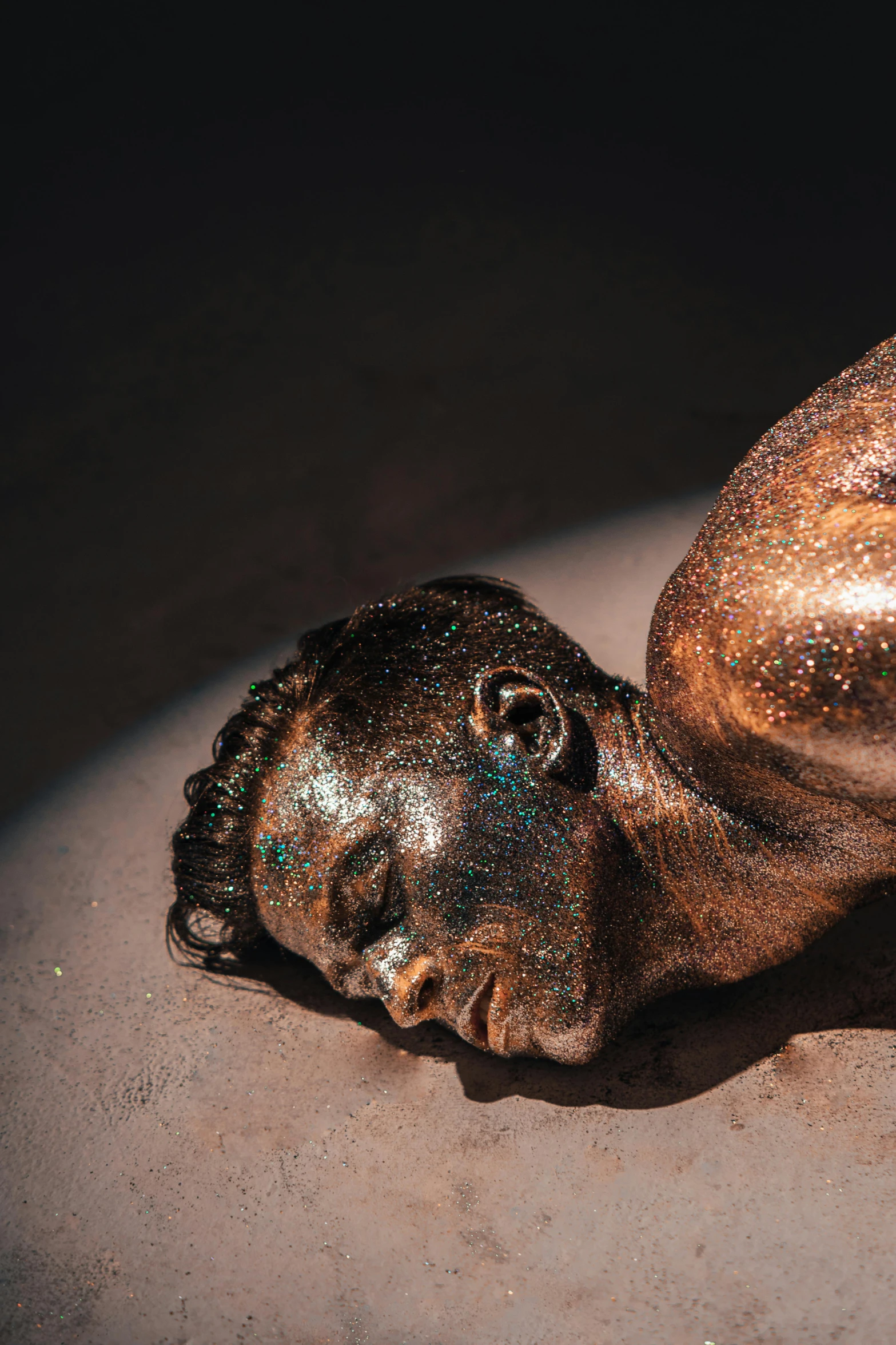 a close up of a statue of a person laying down, iridescent skin, brown skin like soil, glittering metal paint, ignant