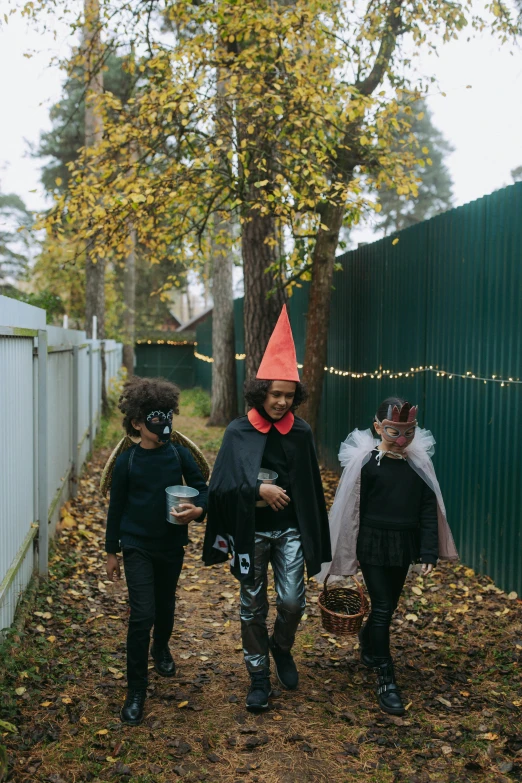 a group of people in costumes walking down a path, by Attila Meszlenyi, trick or treat, cone, high quality photo, a cozy