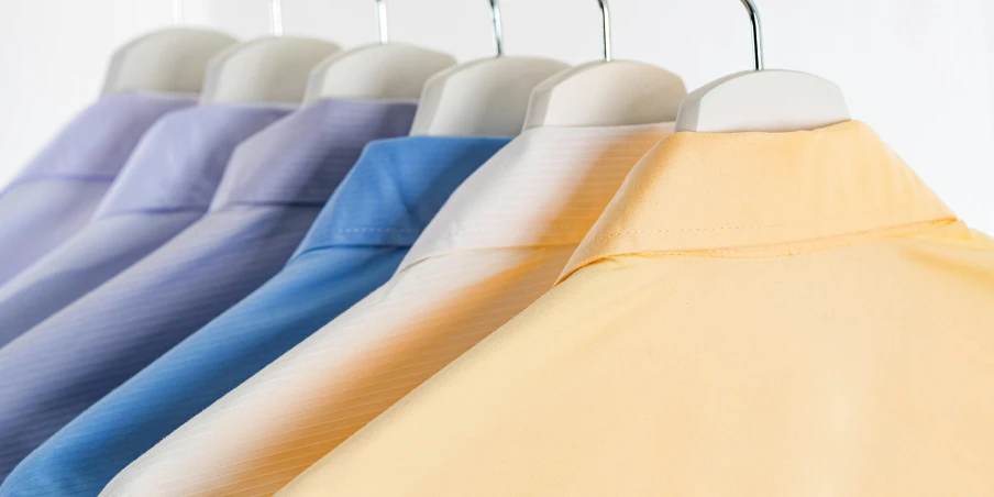 a row of shirts hanging on a clothes rack, sterile colours, ultra detailled, thumbnail, sunrise colors