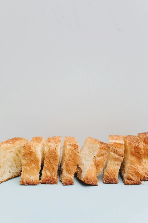 a number of pieces of bread on a table, by Carey Morris, unsplash, photorealism, crisp vector line, from the side, crispy, vanilla