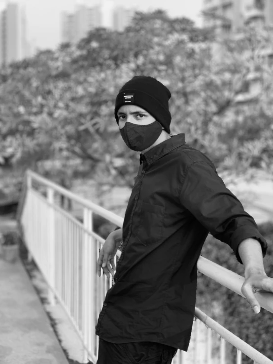 a black and white photo of a man wearing a face mask, a black and white photo, by Ismail Acar, streetwear, connected with hanging bridge!!, black beanie, casual photography