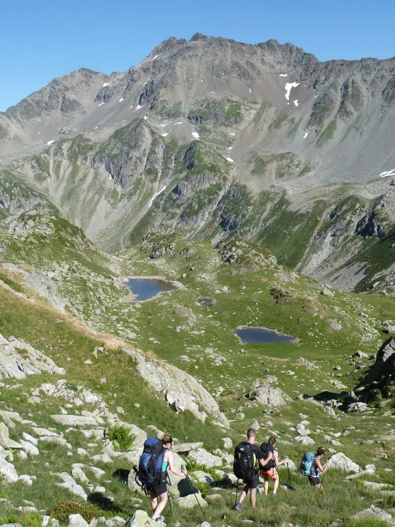 a group of people hiking up the side of a mountain, inspired by Eva Gonzalès, les nabis, near a small lake, top down photo, with mountains in the distance, pyranees