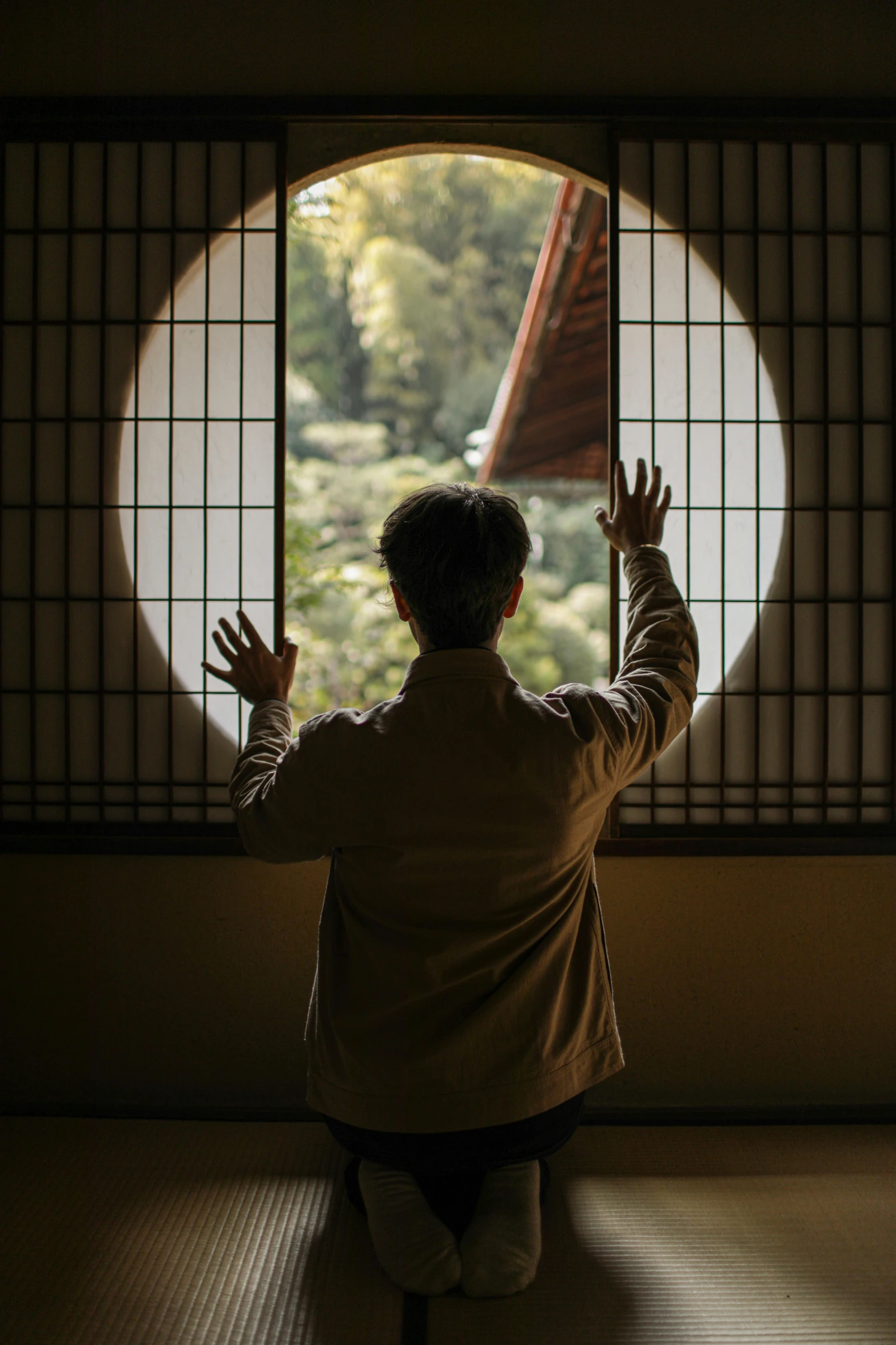 a person standing in front of a window in a room, a picture, inspired by Kanō Shōsenin, trending on unsplash, round windows, in karuizawa, waving, meditating