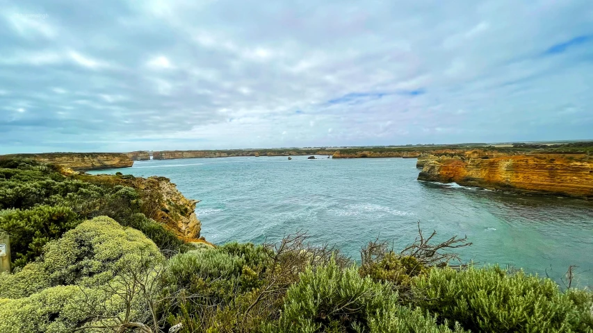 a large body of water sitting on top of a lush green hillside, a tilt shift photo, pexels contest winner, happening, coastal cliffs, “ iron bark, scenic view of river, rock arches