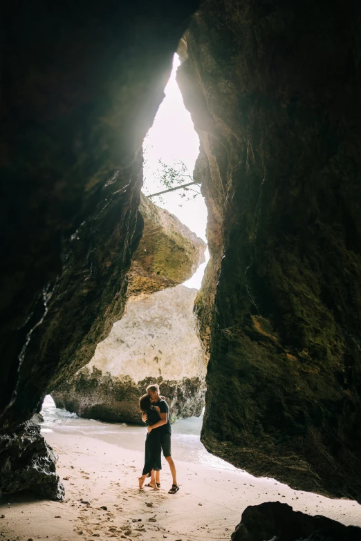 a couple standing in a cave on a beach, tall entry, bali, filled with natural light, inside an epic