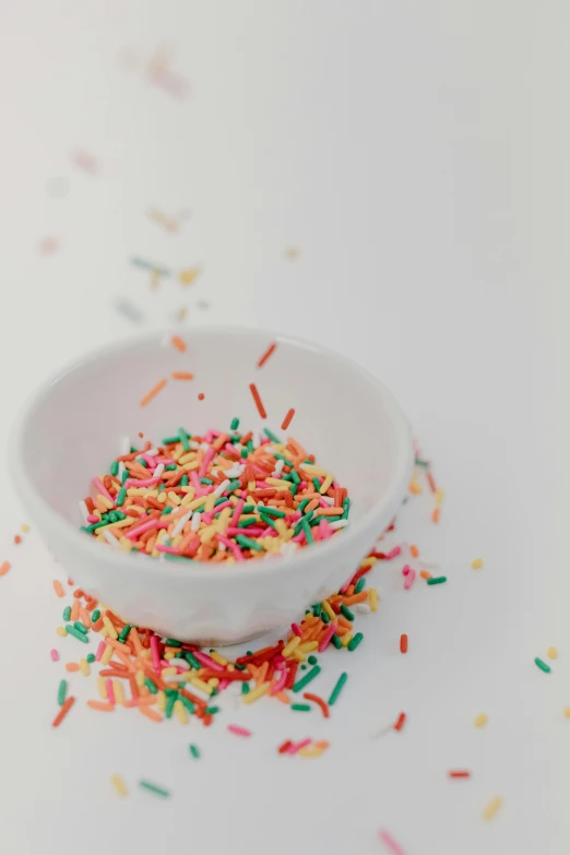 a bowl of sprinkles on a white surface, by Nicolette Macnamara, trending on unsplash, digital image, programming, multiple stories, portrait photo