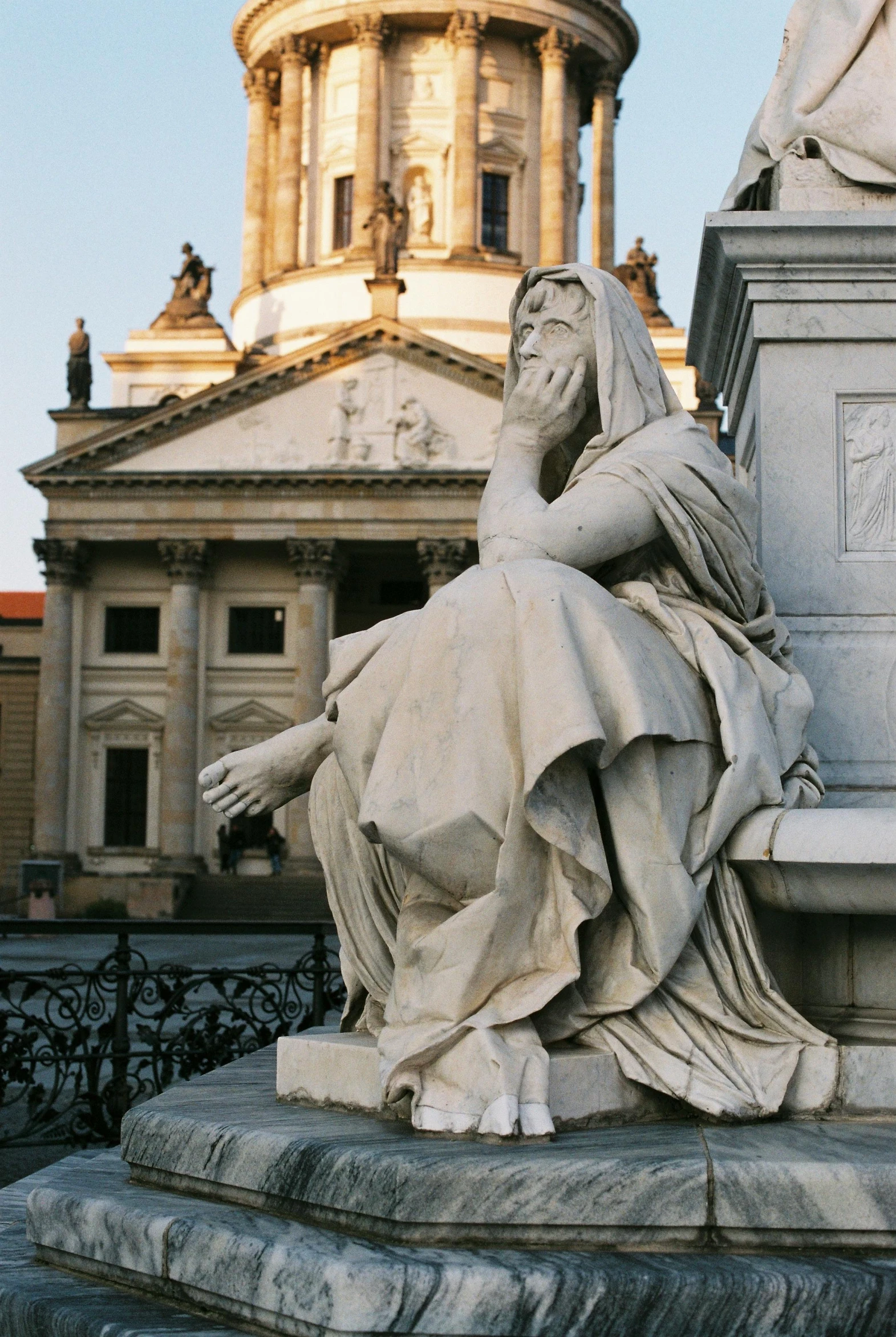 a statue of a woman sitting on a bench in front of a building, inspired by Friedrich Gauermann, neoclassicism, giant grave structures, robed renaissance scholar, she's sad, german renaissance architecture