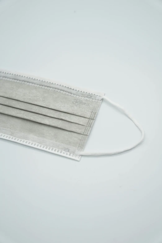 a close up of a face mask on a plate, flat grey color, surgical supplies, textured base ; product photos, rectangle