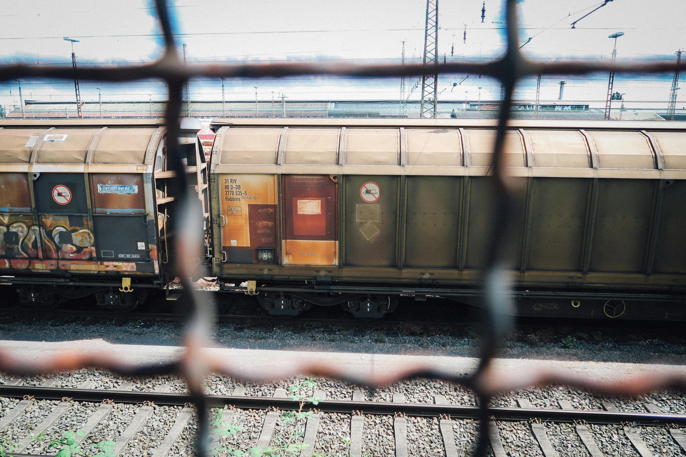 a train traveling down train tracks next to a fence, unsplash, graffiti, view from a news truck, 🚿🗝📝