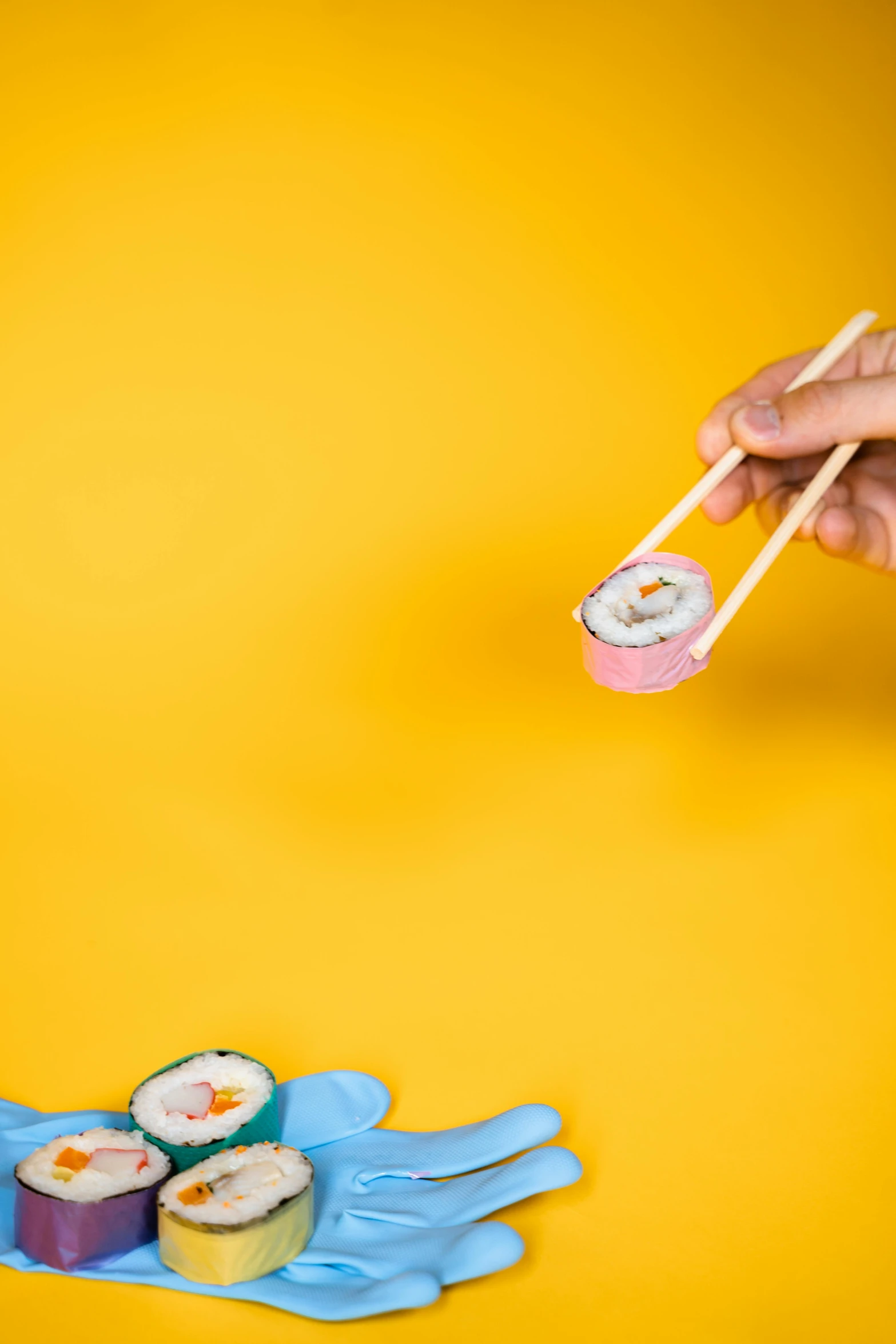 a person holding chopsticks over a plate of sushi, by Julia Pishtar, trending on unsplash, ukiyo-e, yellow backdrop, toy commercial photo, background image, great wave