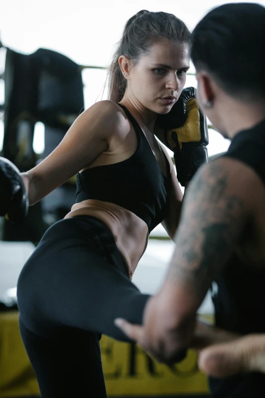 a woman kicking a kick with a man in the background, a tattoo, training bra, thumbnail, tight fit, wētā fx