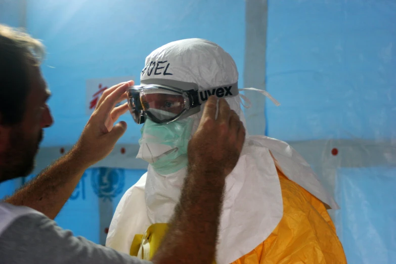 a man putting a mask on another man's face, happening, staff wearing hazmat suits, opaque visor, wearing goggles, avatar image