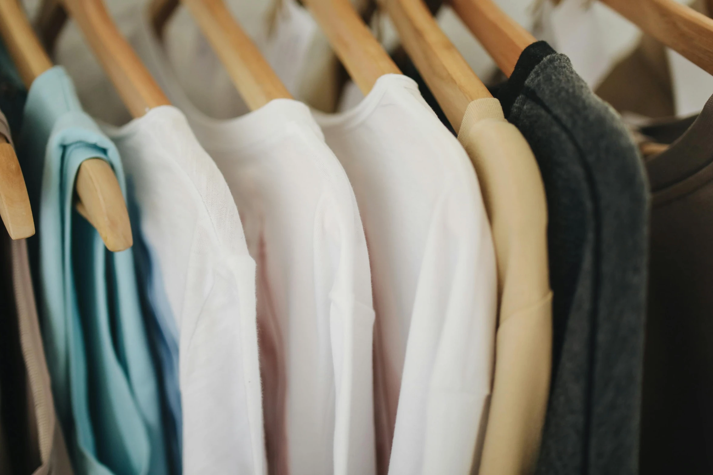 a row of clothes hanging on a rack, a colorized photo, trending on pexels, wearing white shirt, long sleeves, upclose, round-cropped