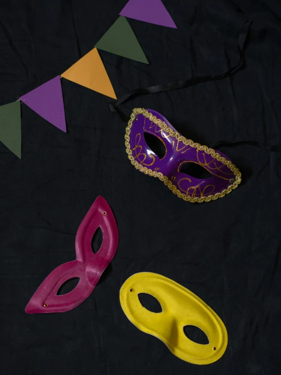 a couple of masks sitting on top of a table, inspired by Andrea del Sarto, trending on unsplash, purple and yellow, party at midnight, detailed product image, high angle close up shot