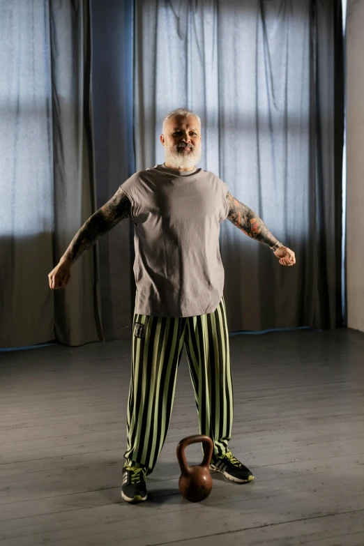 a man standing in a room with a kettle, a hologram, inspired by Graham Forsythe, renaissance, stripey pants, old gigachad with grey beard, arms stretched out, wearing pajamas