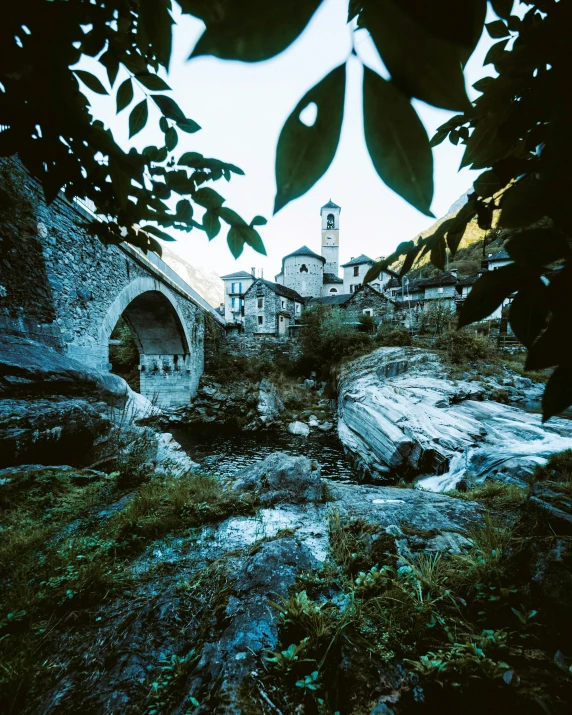 a stone bridge over a river with a building in the background, inspired by Elsa Bleda, romanesque, chamonix, medium format, davide sorrenti, fujicolor photo