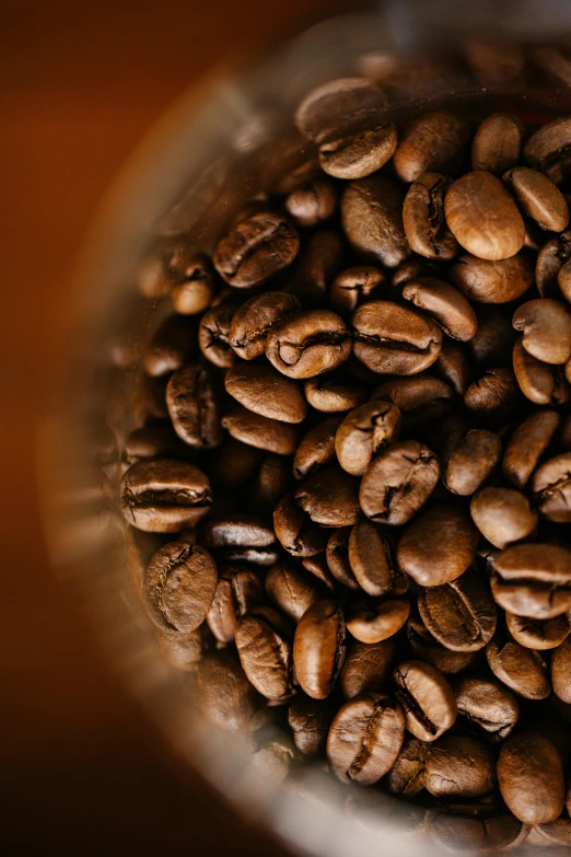 a glass filled with coffee beans on top of a table, by Daniel Seghers, trending on unsplash, portrait closeup, multiple stories, top down shot, colombian