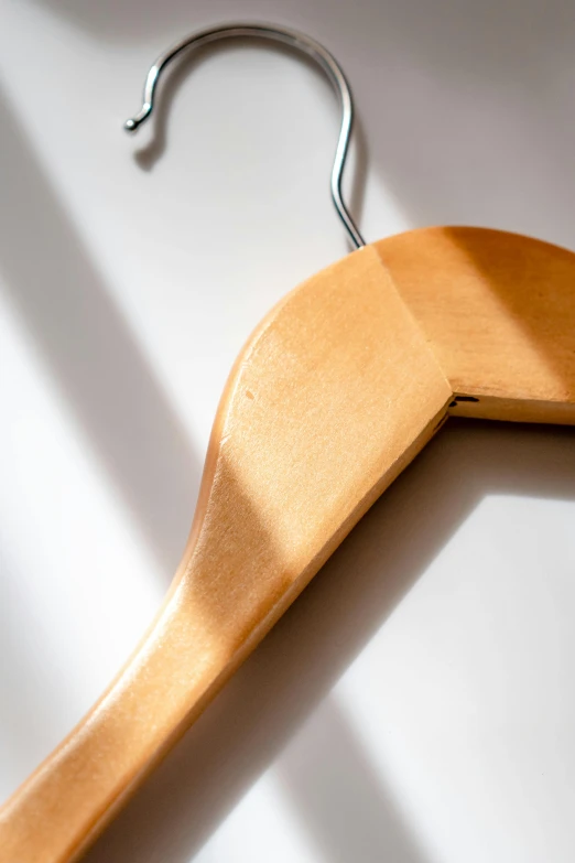 a wooden coat hanger hanging on a wall, by David Simpson, unsplash, visual art, soft shadow, hyperdetailed, backlighted, color photograph