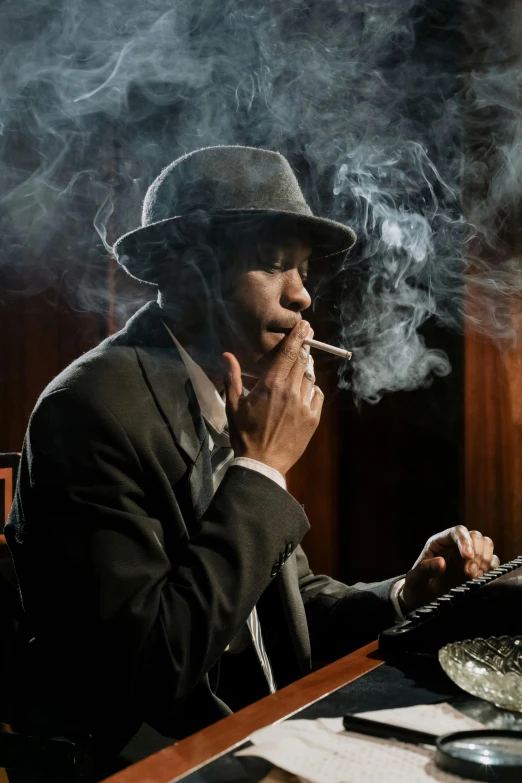 a man sitting at a table smoking a cigarette, inspired by George Bogart, pexels contest winner, harlem renaissance, high hat, ( ( theatrical ) ), smokey room, jazz album cover