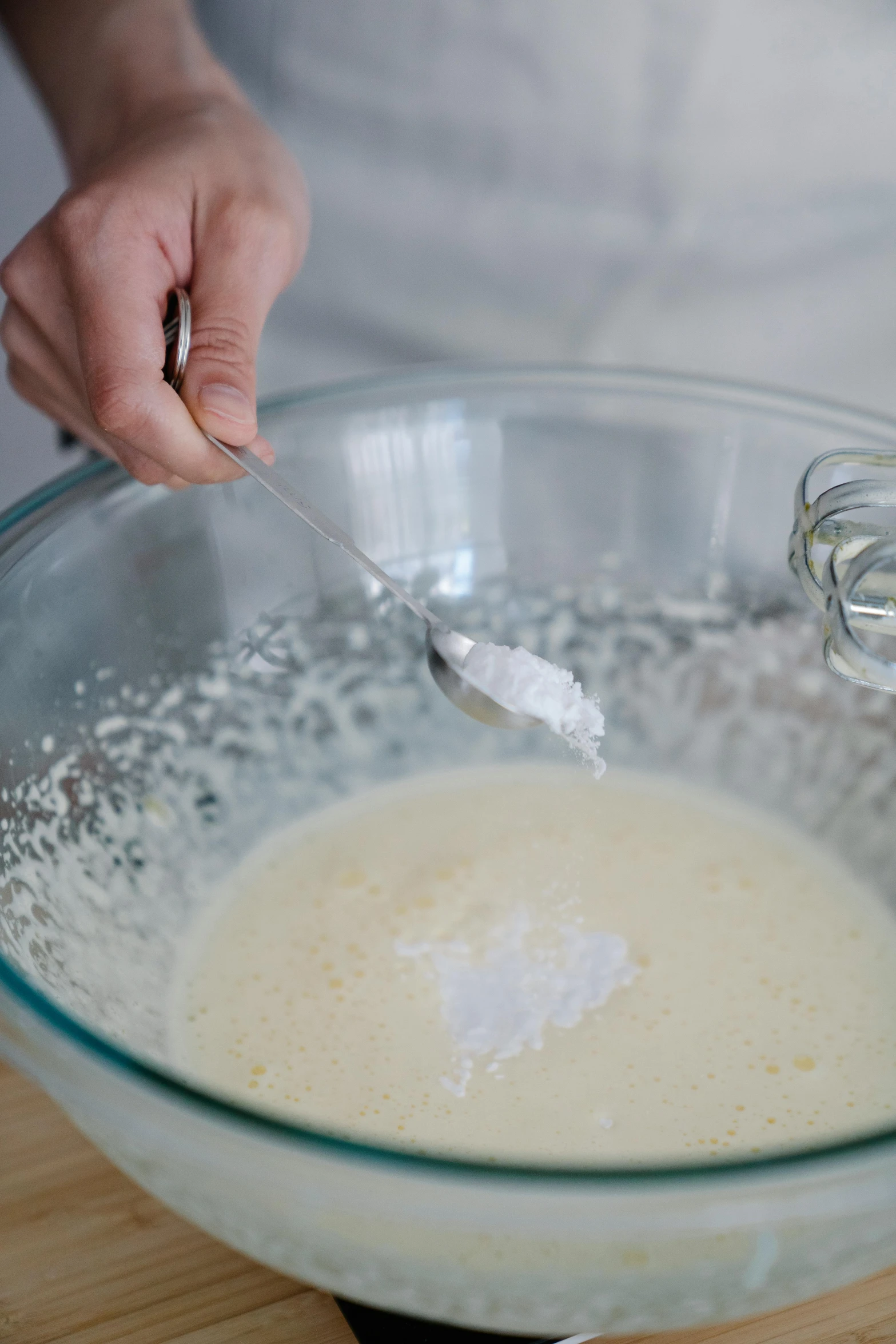 a person mixing a mixture in a glass bowl, silver，ivory, cream of the crop, no cropping, battered