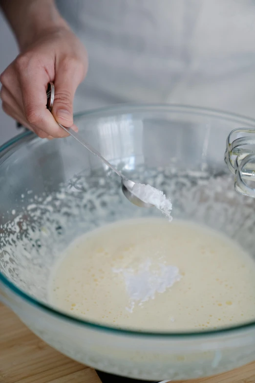 a person mixing a mixture in a glass bowl, silver，ivory, cream of the crop, no cropping, battered