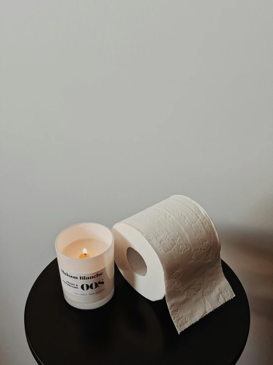 a candle sitting on top of a table next to a roll of toilet paper, by Nina Hamnett, jovana rikalo, embossed, product image