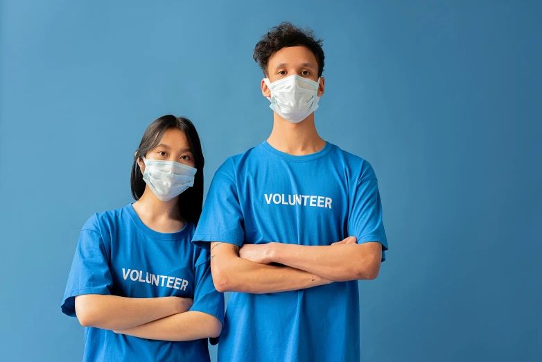 a man and a woman wearing face masks, pexels contest winner, blue uniform, background image, wearing a t-shirt, humans:-1