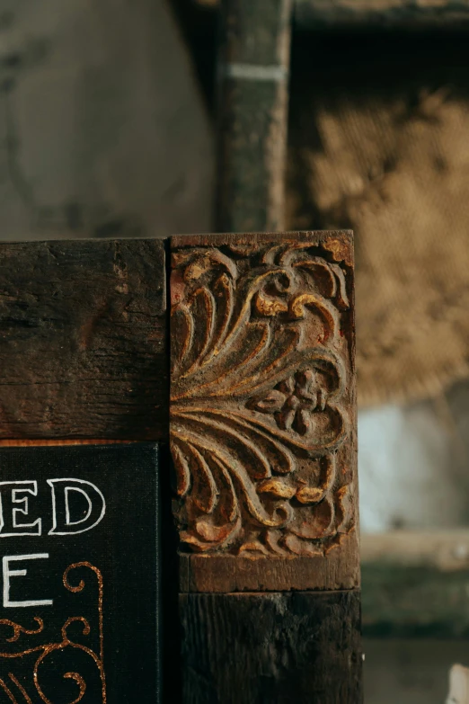 a sign sitting on top of a wooden table, by Jessie Algie, trending on pexels, arts and crafts movement, intricate scrollwork, woodfired, rugged details, on textured base; store website