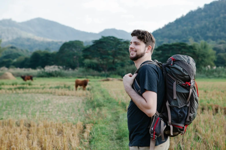 a man with a backpack standing in a field, pexels contest winner, both men and cattle, avatar image, john krasinski, rex orange county