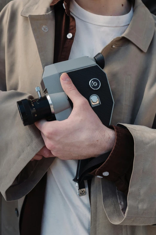 a close up of a person holding a camera, photorealistic blade runner, in style of joel meyerowitz, small gadget, grey