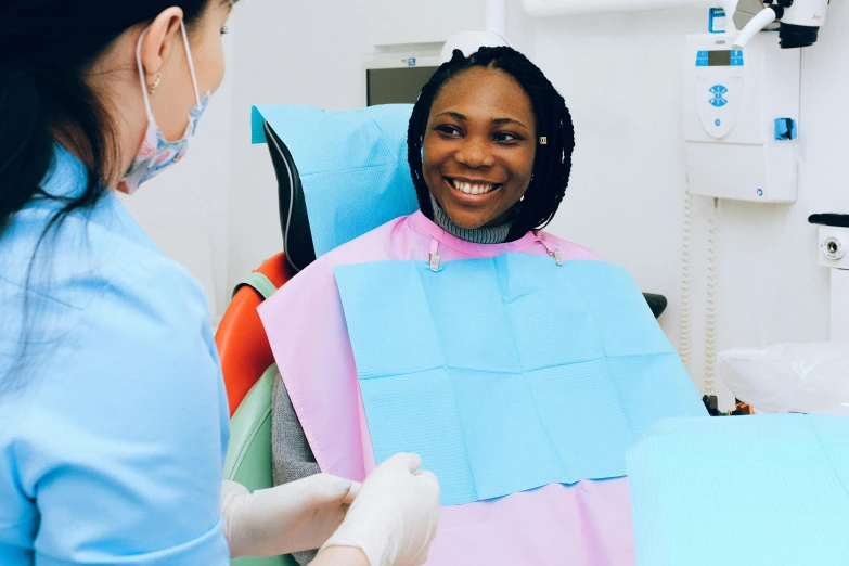 a woman sitting in a chair with a smile on her face, a colorized photo, pexels contest winner, hurufiyya, dentist, emmanuel shiru, clean medical environment, thumbnail