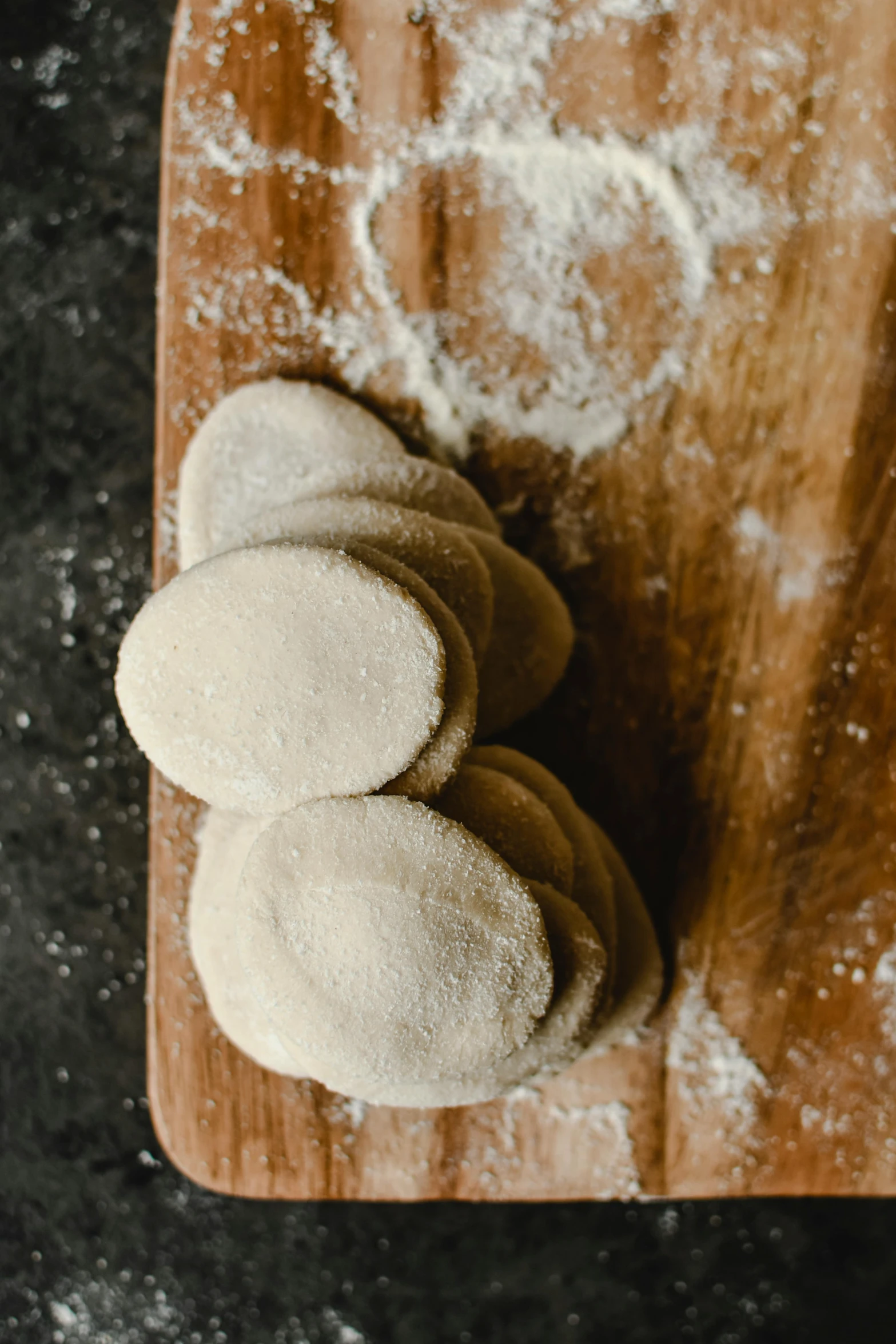 a wooden cutting board topped with doughnuts on top of a table, flour dust, mayan, thumbnail, steamed buns