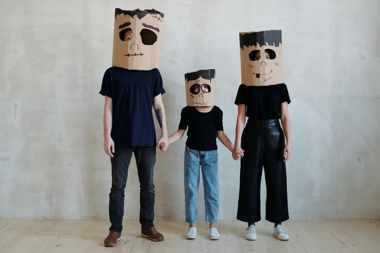 a man and two women with paper bags on their heads, an album cover, by Nina Hamnett, pexels contest winner, neo-dada, groot costume, husband wife and son, made of cardboard, illustration:.4