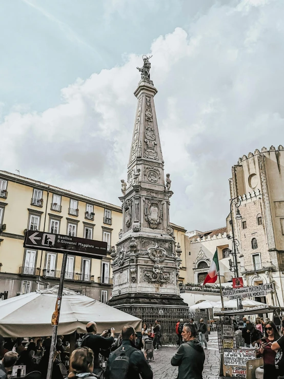 a group of people standing in front of a monument, a statue, by Bernardo Cavallino, pexels contest winner, renaissance, market square, brutalist buildings tower over, gif, nazare (portugal)