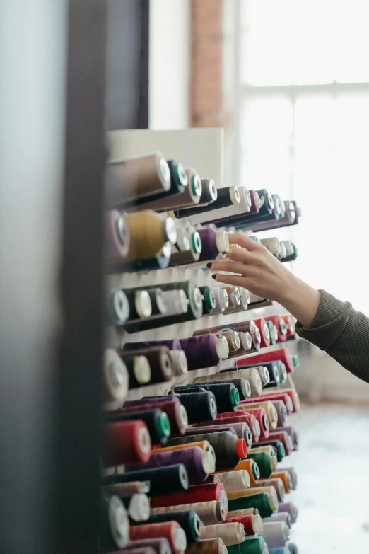 a woman standing in front of a bunch of spools of thread, trending on pexels, inspect in inventory image, opening shot, instagram photo, premium quality