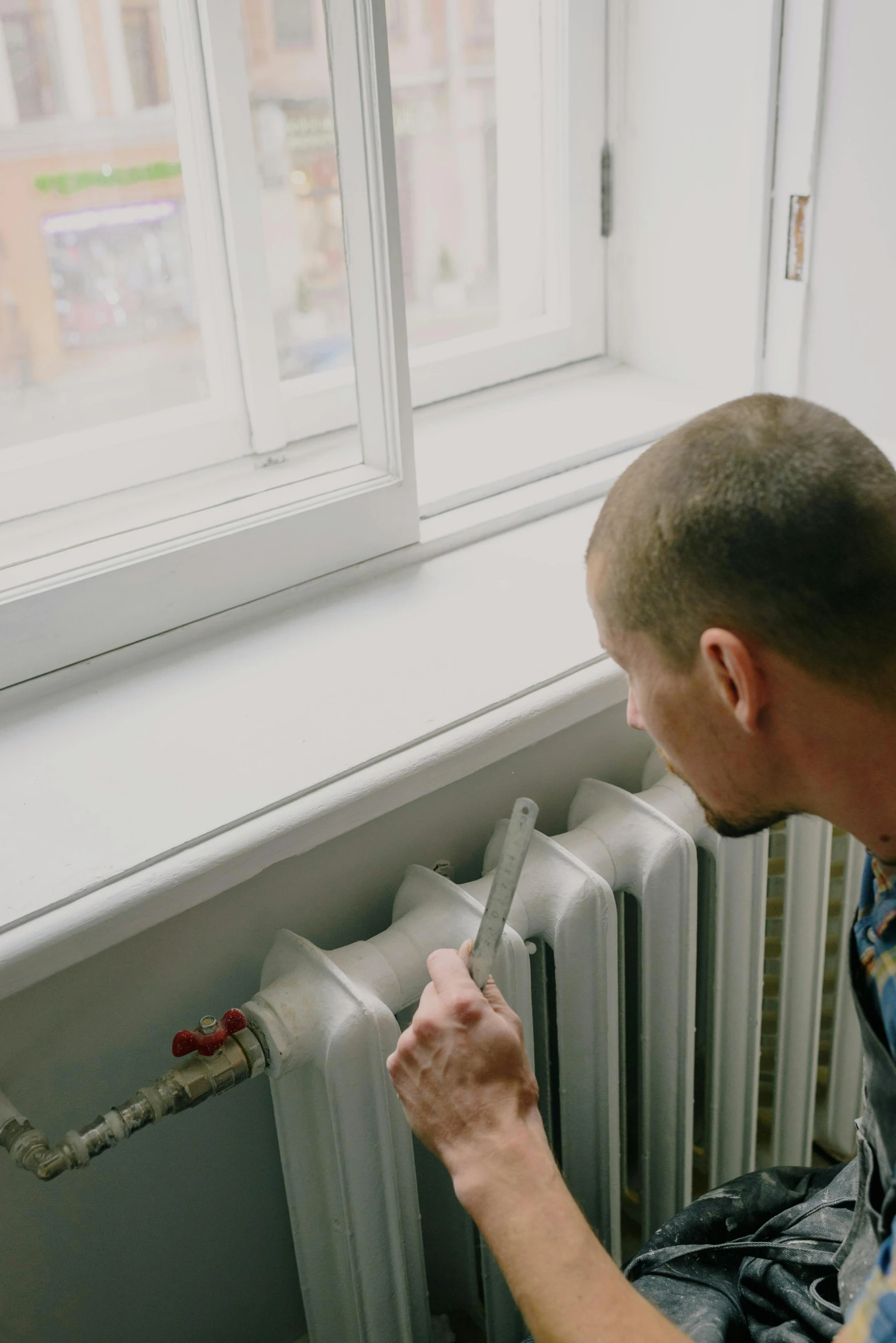 a man fixing a radiator in front of a window, inspired by Elsa Bleda, pexels contest winner, renaissance, low quality video, ignant, developers, with pipes attached to it