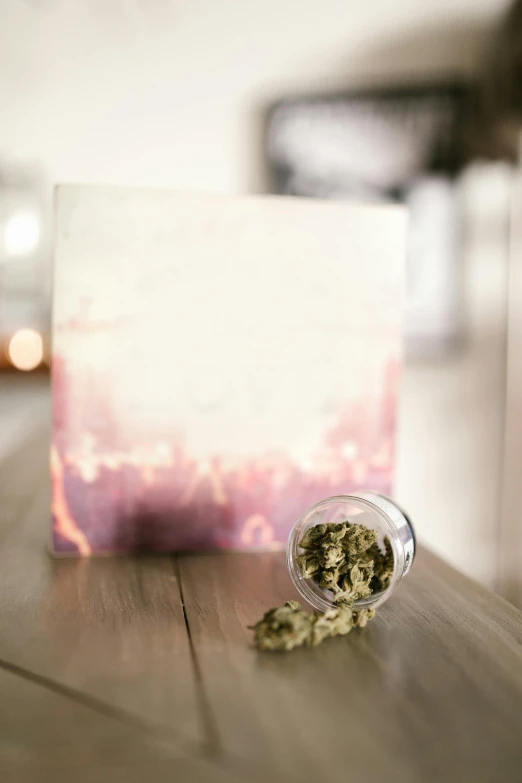 a jar of marijuana sitting on top of a wooden table, an album cover, unsplash, private press, love theme, soft blur, on canvas, indoor picture