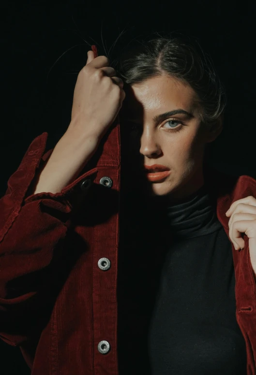 a woman standing in front of a black background, an album cover, inspired by Elsa Bleda, trending on pexels, photorealism, red jacket, handsome girl, fall season, focus on model