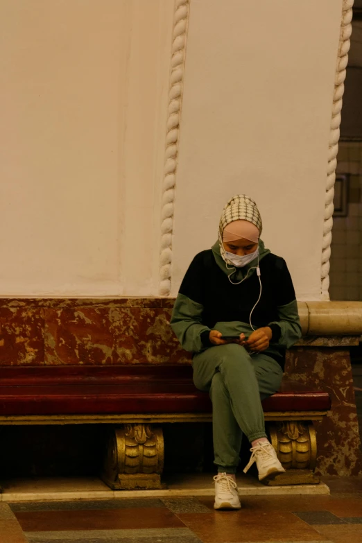 a man sitting on top of a wooden bench, an album cover, by Maryam Hashemi, pexels, hyperrealism, surgical mask covering mouth, moroccan mosque, checking her phone, in the argentine congress