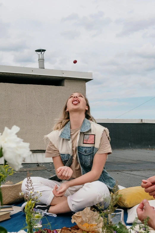 a group of people sitting on top of a blue blanket, girl sitting on a rooftop, earing a shirt laughing, sydney sweeney, with flowers