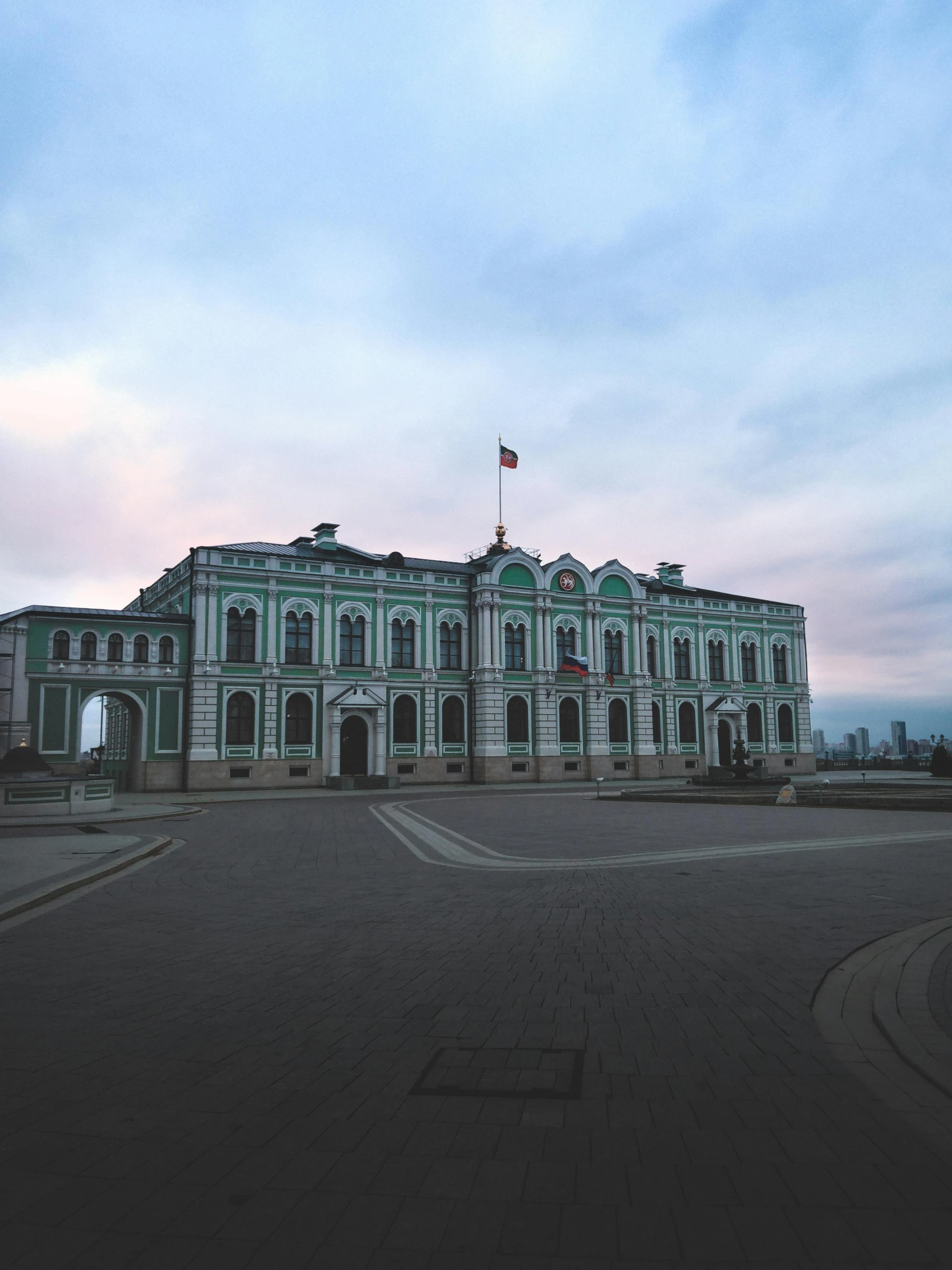 a large building with a flag on top of it, by Andrei Kolkoutine, unsplash, overcast dusk, square, palace background, shipyard