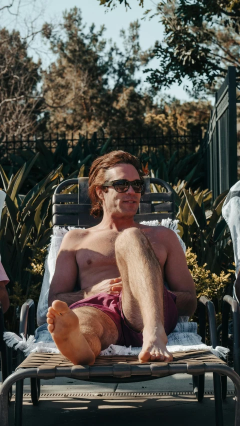a man sitting on top of a chair next to a teddy bear, next to a pool, david spade, lachlan bailey, profile image