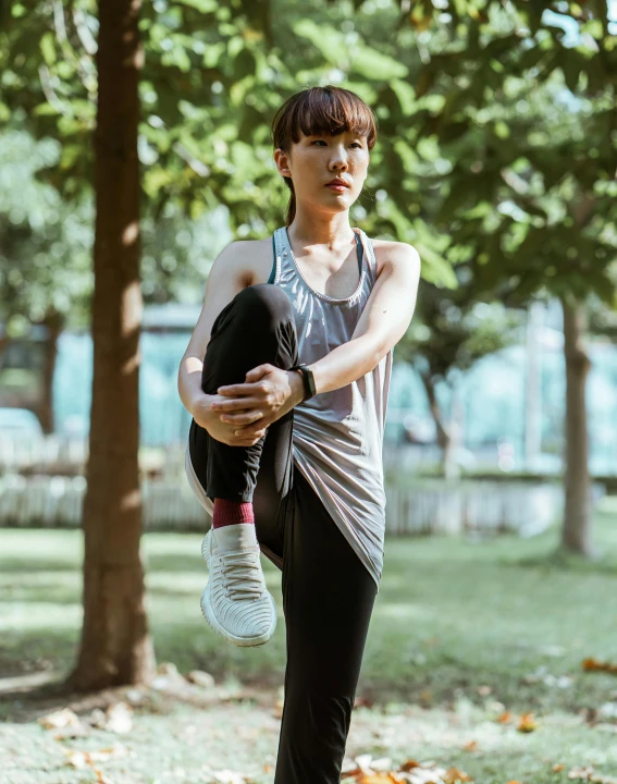 a woman doing a yoga pose in a park, by Natasha Tan, pexels contest winner, non binary model, cai xukun, wearing a muscle tee shirt, shows a leg