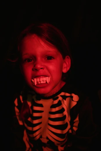 a little girl wearing a skeleton costume in the dark, vampire teeth, zachary corzine, brightly lit!, slide show