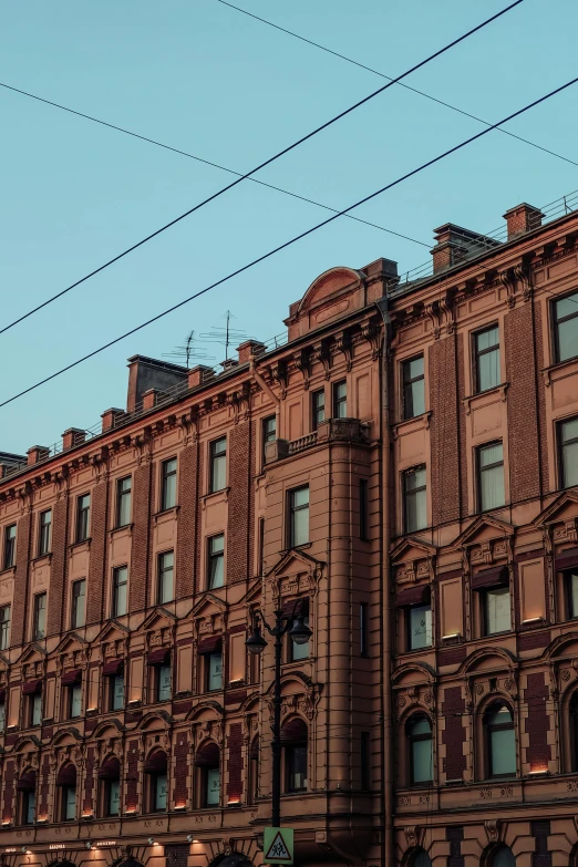 a tall brick building sitting on the side of a street, pexels contest winner, neoclassicism, russia, electrical wires, low quality photo, brown and pink color scheme