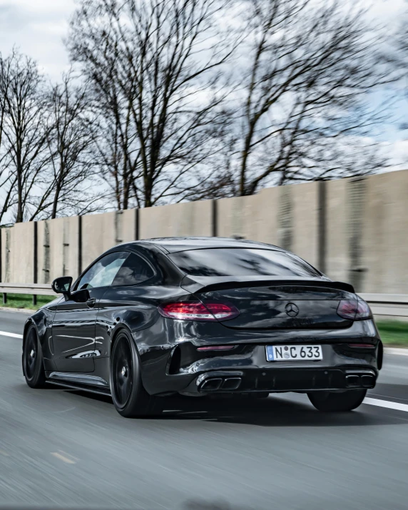 a black car driving down a road with trees in the background, large tail, mercedes, thumbnail, profile image